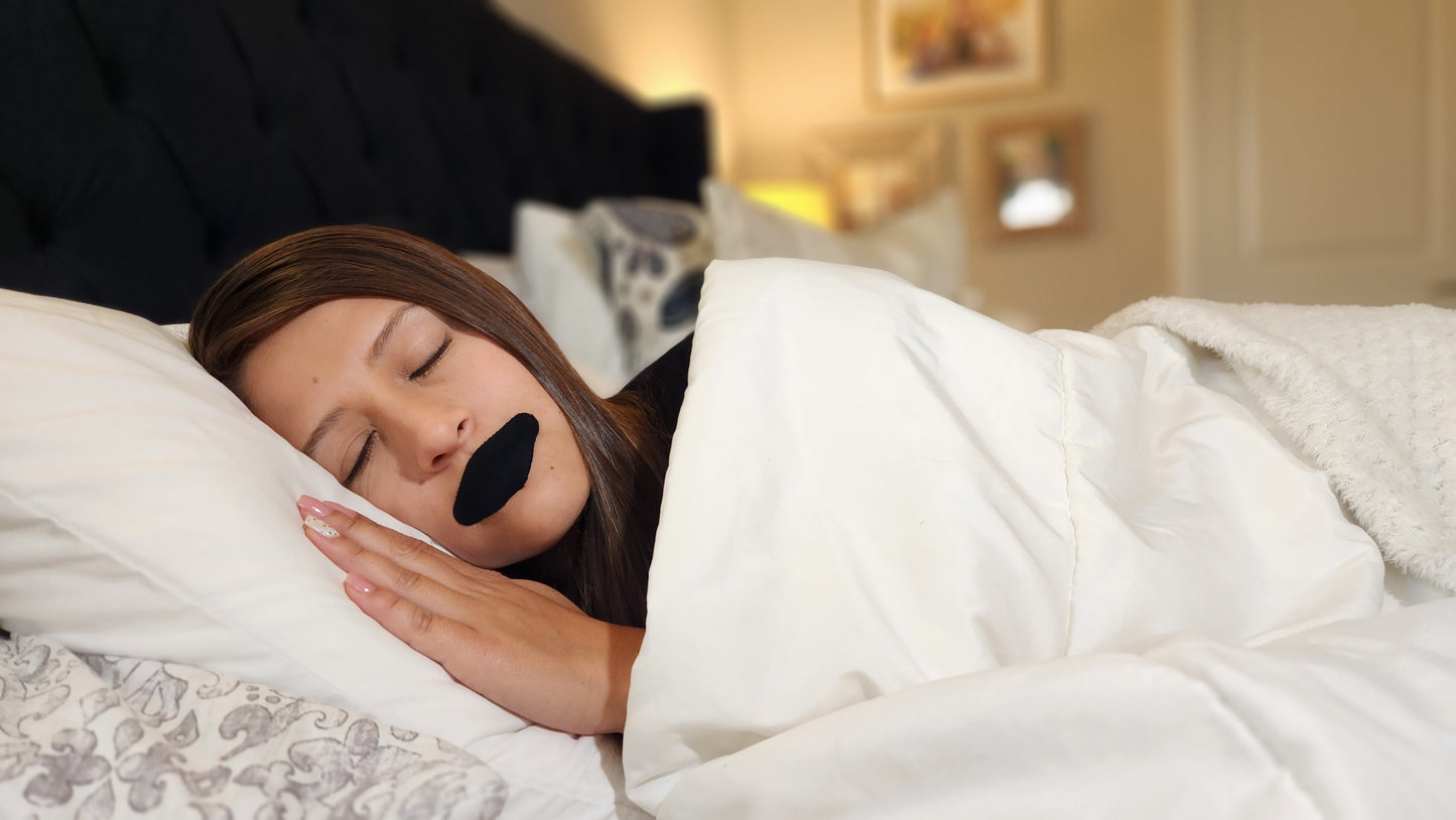a woman sleeping in a bed with a black mouth-taping