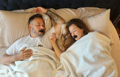 a man and woman lying in bed with black tape over their mouth